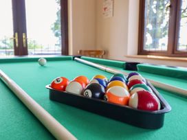 A pool table with balls and cue sticks in a game room at Ty Berllan in Caersws