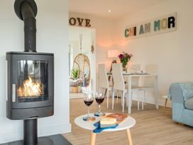 A living room with a wood stove and dining table at Chi An Mor in Porth