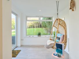A snug with a hanging chair and window overlooking the garden at Chi An Mor in Porth