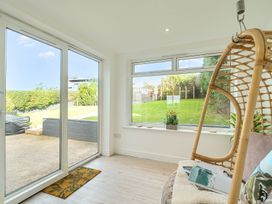 A conservatory with a hanging chair and a view of the garden at Chi An Mor in Porth