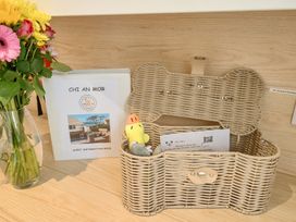 A basket with a guest information book and flowers at Chi An Mor in Porth