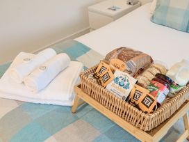 A basket with food items and towels on a bed at Chi An Mor in Porth