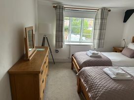 A bedroom with two beds and a dresser at Bramble Cottage in Burton Bradstock