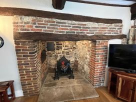 A fireplace with a wooden beam and stone wall at Ivy Cottage in West Lulworth