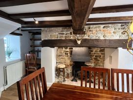 A dining room with a fireplace and wooden furniture at Ivy Cottage West Lulworth