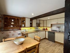 A kitchen with cabinets and table at Ivy Cottage in West Lulworth