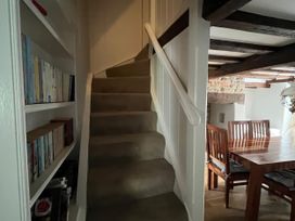 A staircase with a bookshelf and dining area at Ivy Cottage in West Lulworth