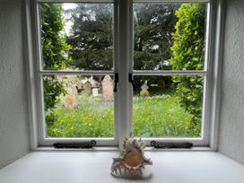 A window view of a graveyard with a shell on the sill at Ivy Cottage in West Lulworth