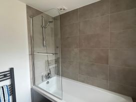 A bathtub with a shower enclosure at Ivy Cottage in West Lulworth