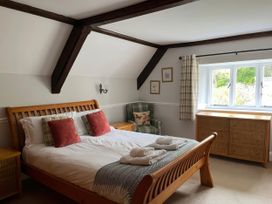 A bedroom with a bed and armchair at Ivy Cottage in West Lulworth