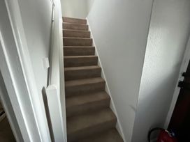 A stairway with beige carpet and a light switch at Little Ivy in West Lulworth