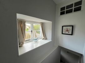 A staircase with a window and a sailboat decoration at Little Ivy in West Lulworth