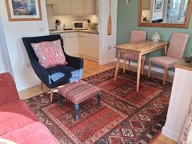A dining room with an armchair and table at Little Retreat Upwey