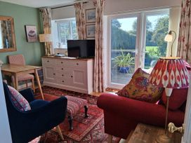 A living room with a sofa and television at Little Retreat in Upwey