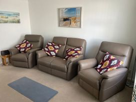A living room with three leather sofas and a painting at Maisy Cottage in Weymouth