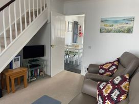 A living room with a television and a staircase at Maisy Cottage in Weymouth