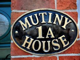 A plaque displaying 'Mutiny House 1A' on a brick wall at Mutiny House in Brewers Quay Harbour