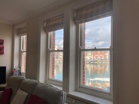 A living room with windows overlooking a harbor at Mutiny House in Brewers Quay Harbour