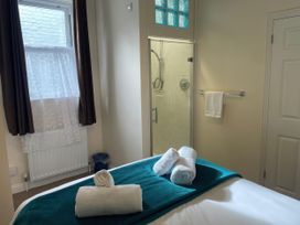 A bedroom with towels on a bed and a shower in the corner at Mutiny House Brewers Quay Harbour