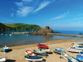 A beach with boats on the sand and people walking at Estuary View in Kingsbridge