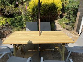A table with chairs and an umbrella in a garden at Pebbles Burton Bradstock