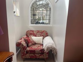 An armchair with a cushion and blanket at Pedaller's Cottage in Weymouth