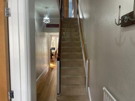 A hallway with a staircase and light fixture at Pedaller's Cottage in Weymouth
