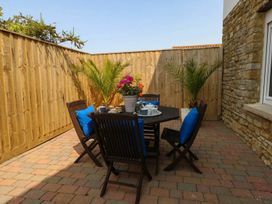An outdoor seating area with a table and chairs at Tides Corner in Bowleaze