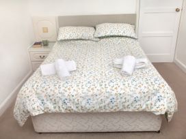 A bedroom with a bed, bedside table, and towels at Weymouth Bay Apartment C in Greenhill