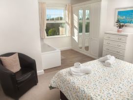 A bedroom with a bed, armchair, and wardrobe at Weymouth Bay Apartment C in Greenhill