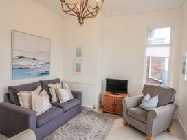 A living room with a sofa, armchair, and television at 1 Hazeldene Salcombe