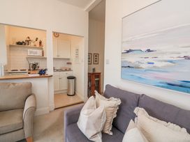 A living room with a sofa and kitchen area at 1 Hazeldene Salcombe