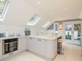 A kitchen with appliances and bar stools at 1 The Old Coach House Dartmouth