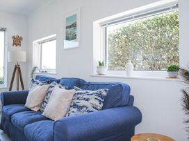 A blue sofa with cushions next to windows and a floor lamp at 2 Rockmount in Salcombe