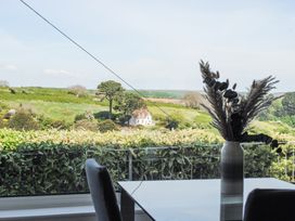 A vase with dried plants on a table by a window overlooking a green landscape with a house in the distance at 2 Rockmount in Salcombe