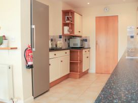 A kitchen with a refrigerator microwave toaster fire extinguisher cabinets and a door at 2 Sea Gardens in Hope Cove