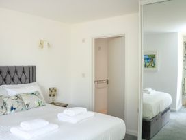A bedroom with a made bed with pillows and towels with a bedside table and lamp at 2 Sea Gardens in Hope Cove