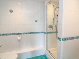 A bathroom with tiled walls and a shower enclosure at 2 Sea Gardens in Hope Cove