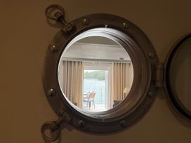 A view of a balcony with a chair and lamp seen through a circular window at 35 The Salcombe, Salcombe