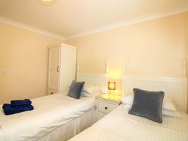 A bedroom with two beds, a wardrobe, and a lamp at 4 Bolt Head in Salcombe
