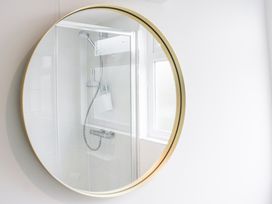 A bathroom with a shower and a round mirror at 4 Lyndhurst Salcombe