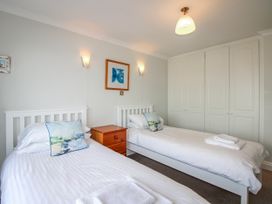 A bedroom with two beds and a bedside table at 7 Thurlestone Rock in Thurlestone