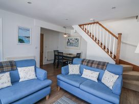A living room with blue sofas and a dining area at Armada Cottage Dartmouth