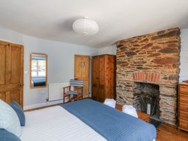 A bedroom with a bed, wardrobe, mirror, and chair at Armada Cottage Dartmouth