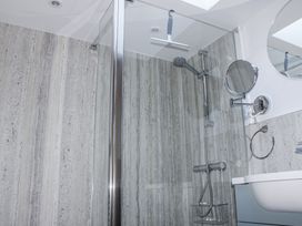 A shower with glass door and wall panel at Armada Cottage Dartmouth