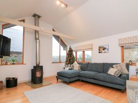 A living room with a corner sofa and a Christmas tree at Courtyard Cottage in Dartmouth