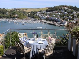 An outdoor patio with a table and chairs overlooking the water at Dart Views in Dartmouth