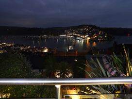 A view of boats and houses at night from a balcony at Dart Views in Dartmouth
