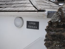 A sign for Upper Fernlea on a white building wall in Salcombe