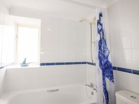 A bathroom with a bathtub and shower curtain at Orchard Barn Salcombe
